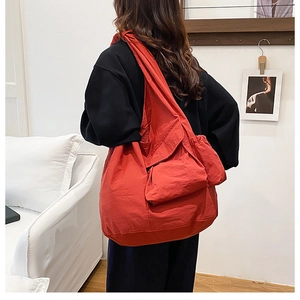 Detail of red oversized tote bag with multiple pockets and pleated texture design