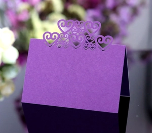 Detailed laser cut purple wedding table card featuring intricate hollow heart patterns
