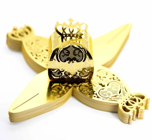 Detail of laser-cut gold crown favor boxes with intricate hollow heart and floral patterns