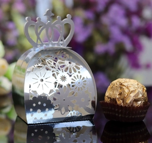 Macro detail of silver crown hollow laser-cut candy box with floral patterns and chocolate