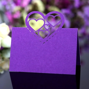 Macro detail of laser-cut hollow heart design on deep purple wedding table place card