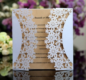 Detail of white laser-cut snowflake invitation sleeve with kraft paper insert