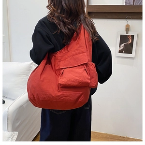 Detail of red oversized nylon tote bag showing wrinkled texture and side pocket