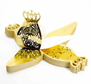 Macro shot of laser-cut crown pattern on gold metallic cardstock for wedding favors