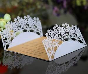 Detail of laser cut white snowflake invitation with gold insert and elegant wedding text