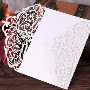 Elegant white laser-cut wedding invitation card with floral hollow-out pattern on wood