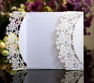Macro shot of white laser-cut snowflake wedding invitation with pearlescent paper detail