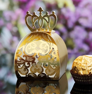 Detail of laser-cut gold crown wedding favor box with intricate hollow lace patterns
