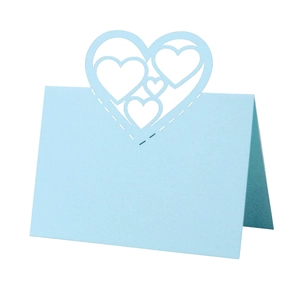 Detailed laser-cut hollow heart design on a light blue wedding place card in macro view