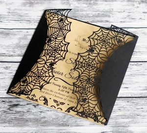 Detail of laser-cut black spider web invitation with vintage kraft paper insert