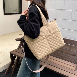 Détail du sac cabas beige matelassé montrant la texture du tissu et la poche extérieure