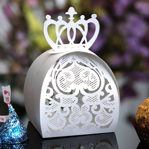 Detail of white laser-cut wedding favor box with crown top and heart pattern