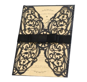 Close-up of laser-cut butterfly invitation card with black ribbon bow and kraft insert