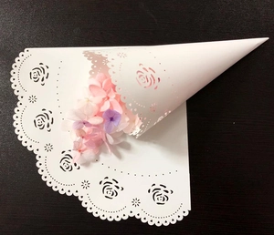 Close-up of white laser-cut lace paper confetti cone with elegant hollow rose patterns