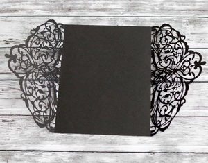 Detail view of black laser-cut floral patterns on an elegant invitation card cover