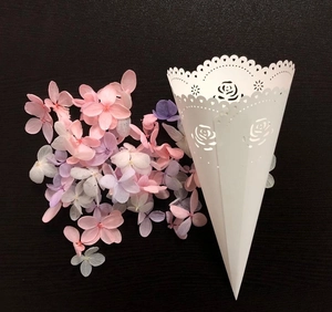 Detail of laser cut white paper cone with rose pattern for wedding petals and confetti