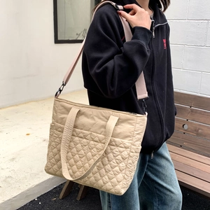 Détail du sac cabas matelassé beige montrant la texture losange et la bandoulière