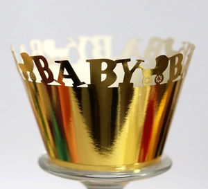 Detailed laser-cut gold cupcake wrapper featuring baby stroller and BABY lettering