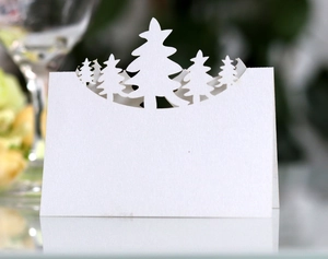 Detail of laser-cut white Christmas tree place cards on elegant festive table setting