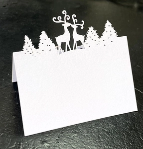 Detail of laser-cut white card with deer and forest silhouettes for Christmas table decor