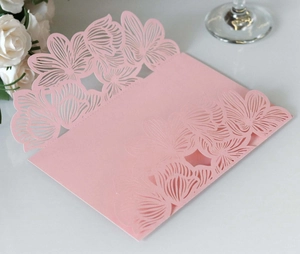 Detail of pink laser-cut wedding invitation featuring intricate floral hollowed patterns