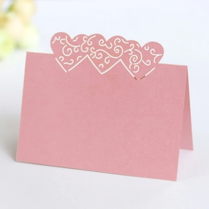 Detailed view of pink laser-cut heart place card with elegant white vine patterns