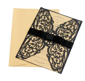 Close-up of laser-cut black butterfly wedding invitation with satin bow and kraft insert
