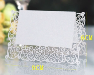 Detail of white butterfly laser-cut wedding place card with elegant lace hollow patterns