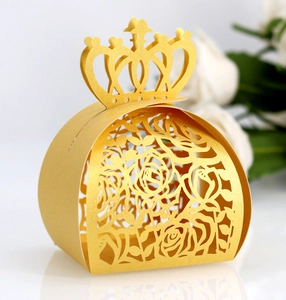 Detail of laser-cut gold wedding favor box featuring hollow rose patterns and crown top