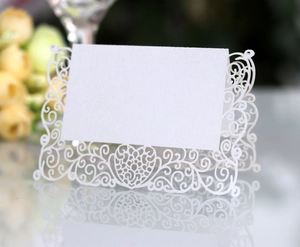 Macro shot of white laser-cut lace heart place card with elegant pearl paper texture