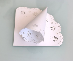 Macro detail of white laser-cut rose hollow pattern wedding confetti cone paper