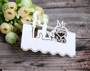 Detail of laser-cut pearl white wedding place card with Mr & Mrs butterfly heart design
