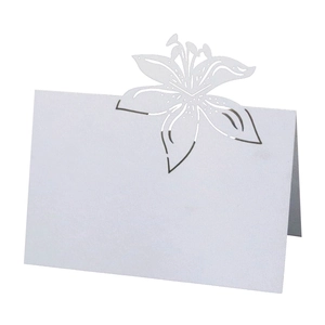 Macro detail of laser-cut lily design on white hollow wedding table name card