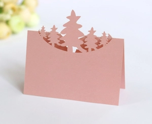 Detail of pink laser-cut Christmas tree place card with textured paper and hollow design