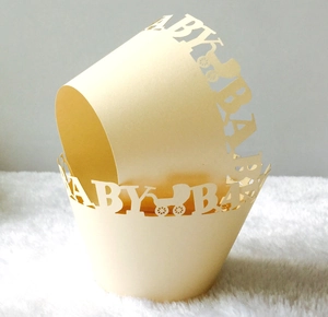 Detail of laser-cut baby shower cupcake liners featuring BABY text and stroller patterns