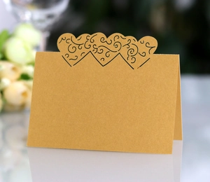 Close-up of laser-cut heart pattern on golden pearlescent place card for weddings