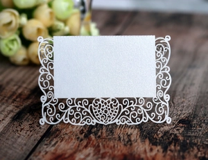 Macro detail of laser-cut white heart lace place card on a rustic wood background