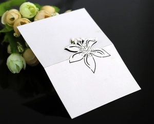 Detailed view of elegant white wedding place card with intricate lily flower line art design