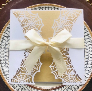 Close-up of laser-cut spider web card with kraft paper and cream satin ribbon