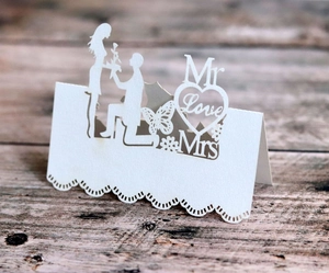 Close-up of laser-cut wedding place cards with Mr and Mrs silhouettes on wood