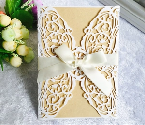 Detail of laser-cut wedding invitation with kraft paper insert and white ribbon bow