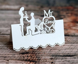 Macro view of laser-cut wedding table card featuring butterflies and heart shapes