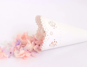 Detailed macro of white laser-cut rose paper confetti cone with elegant hollowed edges