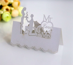 Detail of laser-cut white wedding table card with romantic silhouette and butterfly design