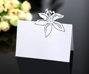 Detail of white laser-cut lily wedding place card standing on a sleek black surface