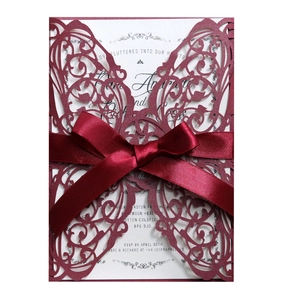 Detail of laser-cut butterfly wedding invitation with burgundy ribbon and cream insert