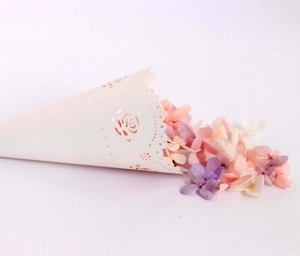 Close-up of laser-cut white rose lace wedding confetti cone with dried flower petals