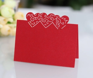 Close-up of red laser-cut heart place card with elegant white vine vine patterns