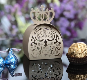 Detail of laser-cut gold crown candy box with intricate lace pattern for wedding favors