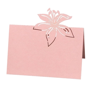 Pink laser-cut lily wedding place card with intricate floral hollow design on white background